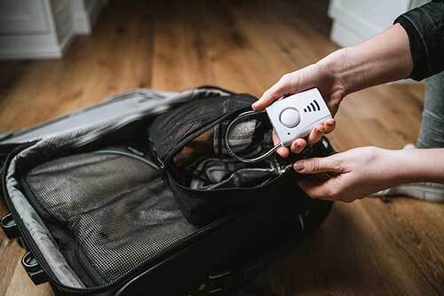 person putting a door handle alarm into a suitcase
